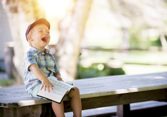 boy sitting on bench while holding a book