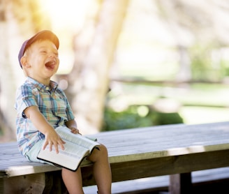 boy sitting on bench while holding a book