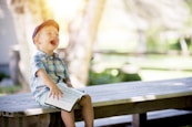 boy sitting on bench while holding a book