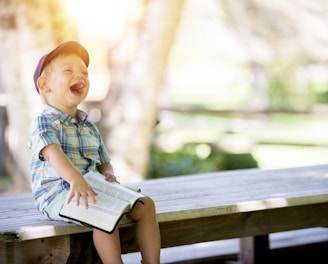 boy sitting on bench while holding a book