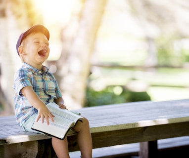 boy sitting on bench while holding a book