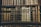 A collection of vintage, leather-bound books arranged neatly on wooden shelves. The spines of the books display intricate gold embossing and titles, showcasing a sense of antiquity and elegance.