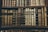 A collection of vintage, leather-bound books arranged neatly on wooden shelves. The spines of the books display intricate gold embossing and titles, showcasing a sense of antiquity and elegance.