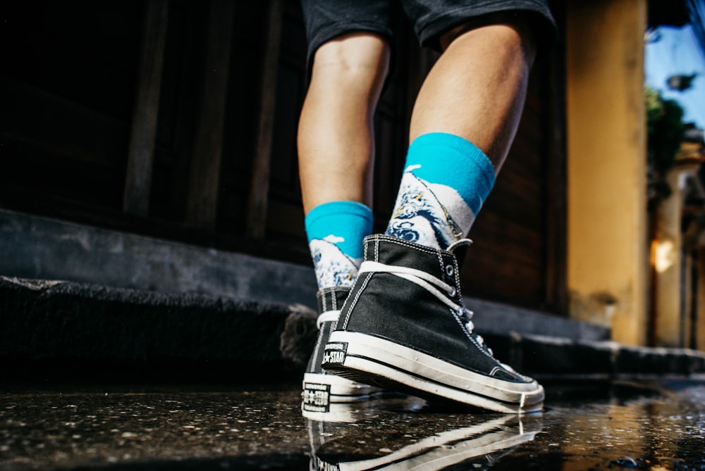 uomo che indossa high-top neri che camminano sulla strada bagnata