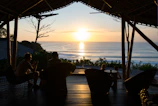 Traveler enjoying a sunset view from a wooden deck overlooking the Indian Ocean.