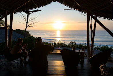 Sunset view from a villa terrace with comfortable seating and ocean horizon.