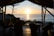 Guests enjoying a serene sunset view from a wooden deck overlooking the calm sea.