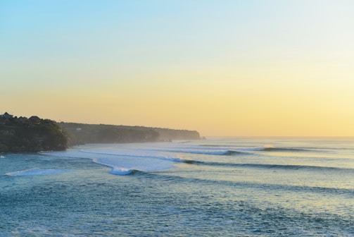 A serene Irish coastline at sunrise with gentle waves and green cliffs.