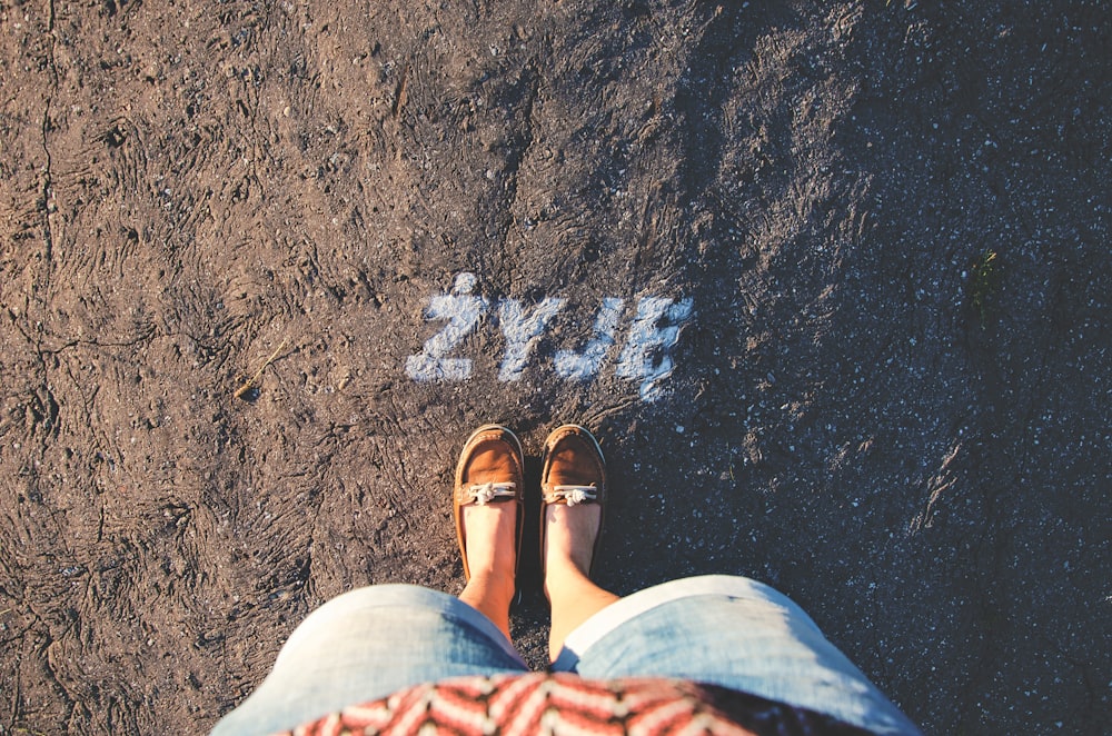 person taking a picture of brown loafers