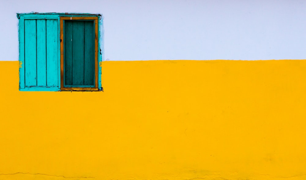 파란색 창문이 있는 노란색과 흰색 페인트 벽