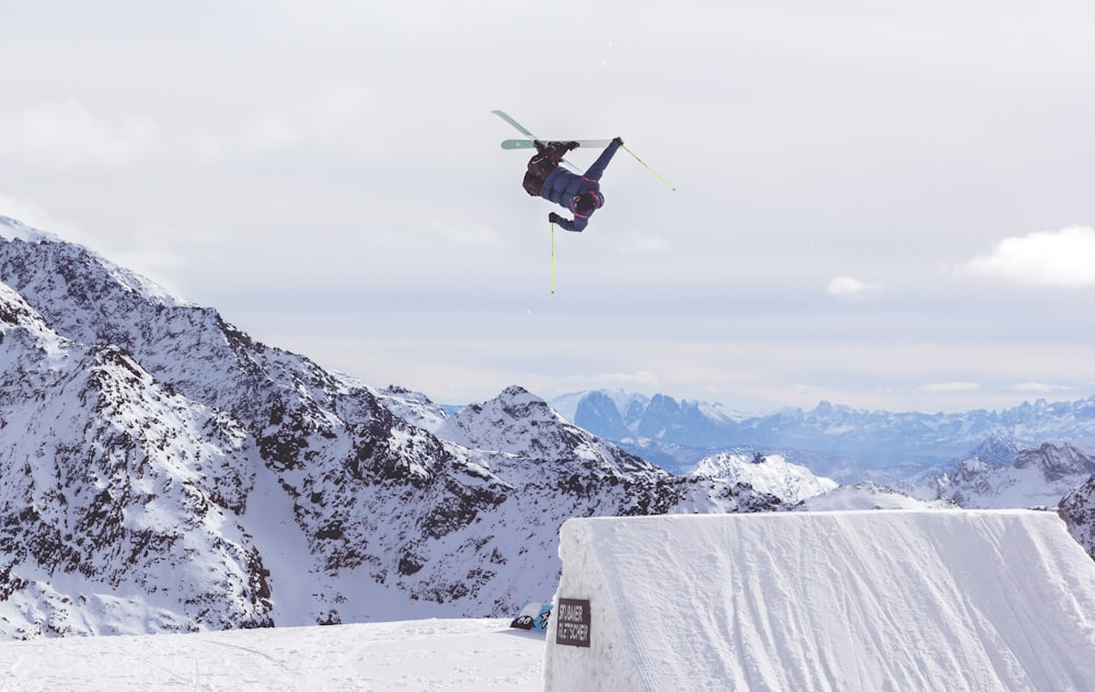 blue helicopter on top of mountains with white snow during daytime