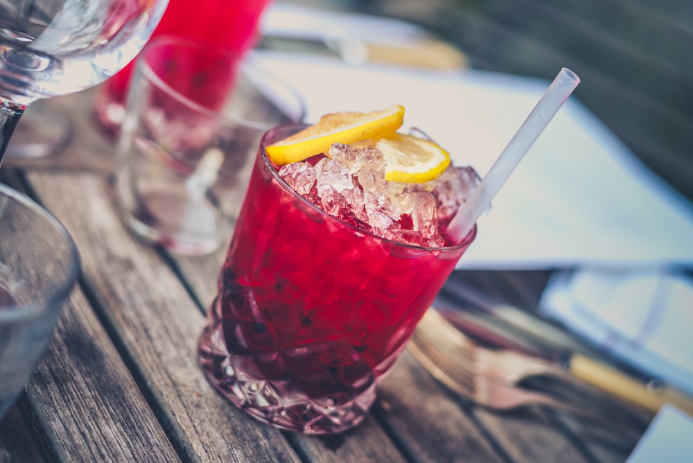 A cranberry cocktail beverage juice with ice and straw in a glass cup