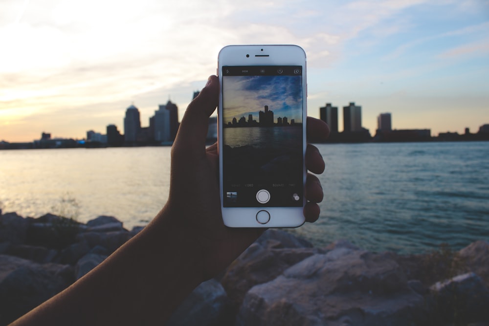 person taking picture of body of water and building