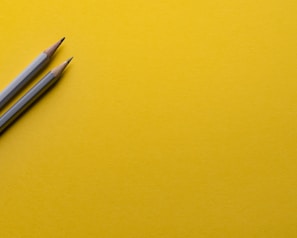 two gray pencils on yellow surface