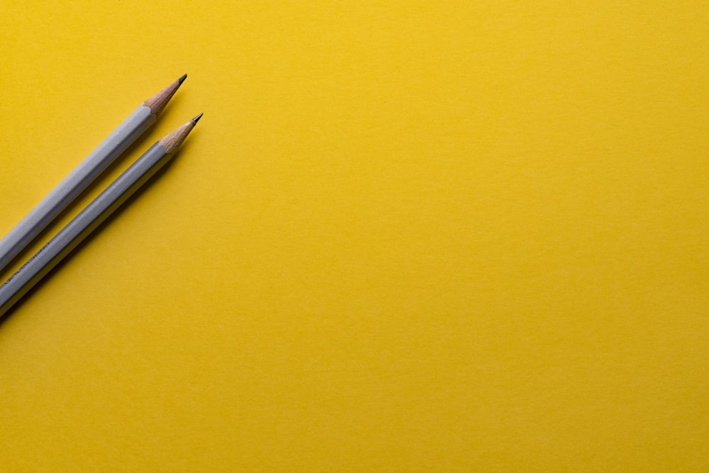 黄色い表面に2本の灰色の鉛筆