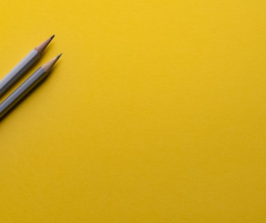 two gray pencils on yellow surface