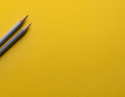 two gray pencils on yellow surface