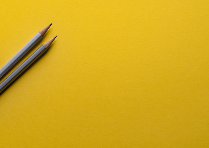 two gray pencils on yellow surface