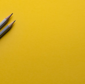 two gray pencils on yellow surface