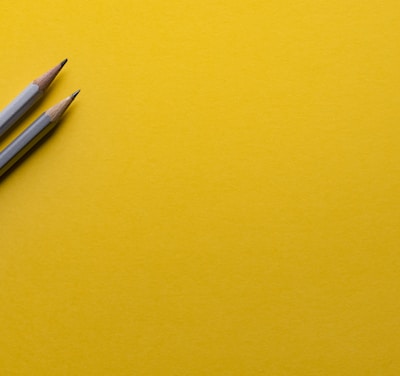 two gray pencils on yellow surface