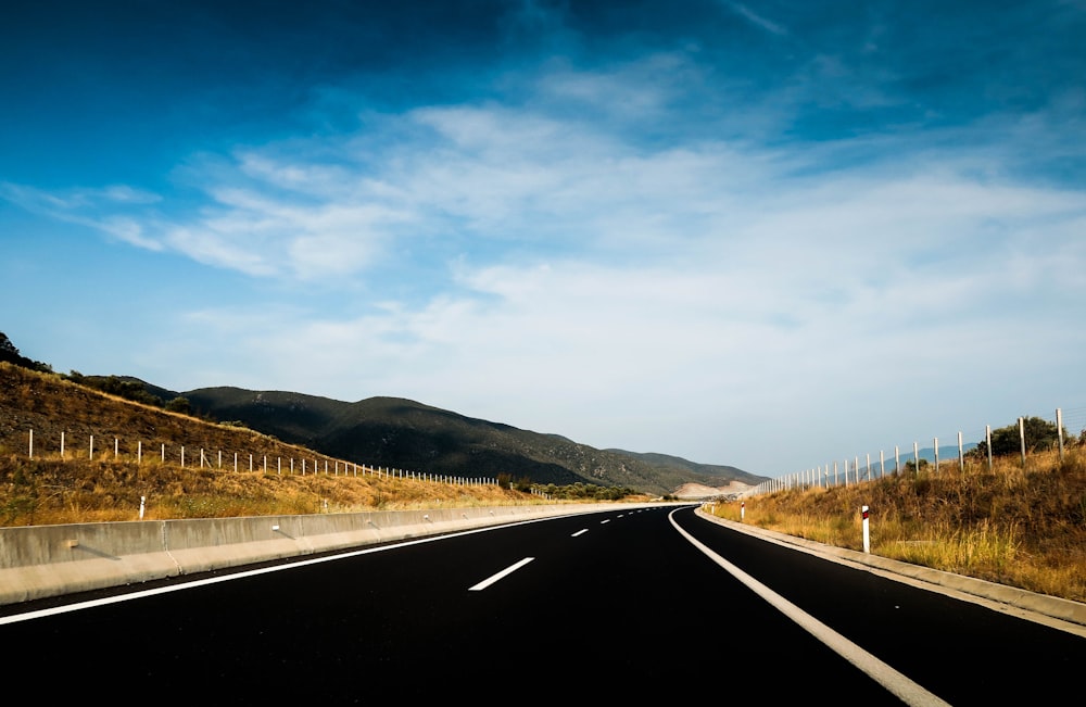 mountain ranges near road under cloudy sky