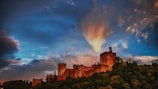 Historic castle ruins perched on a hilltop with dramatic skies overhead.