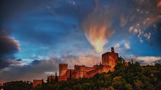 A historic castle perched on a hill under a dramatic sunset.