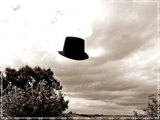 A vintage top hat floating gently against a textured old paper background with faint playing card watermarks.