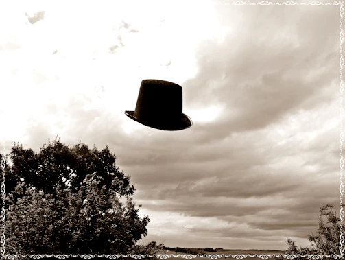 A vintage top hat floating gently against a textured old paper background with faint playing card watermarks.