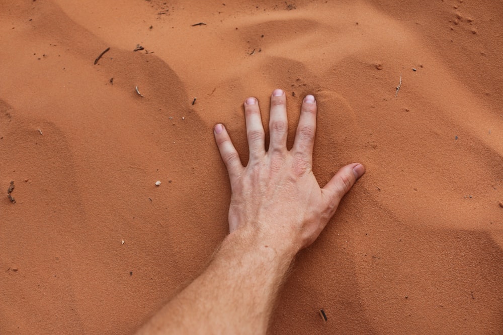 Eine Person, die ihre Hand auf Sand legt.