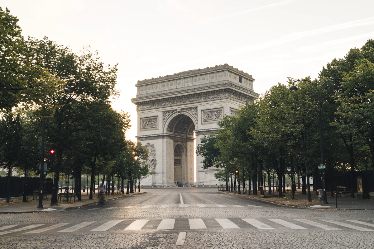 The Arc de Triomphe at the center of its roundabout in Paris, framed by grand tree-lined boulevards