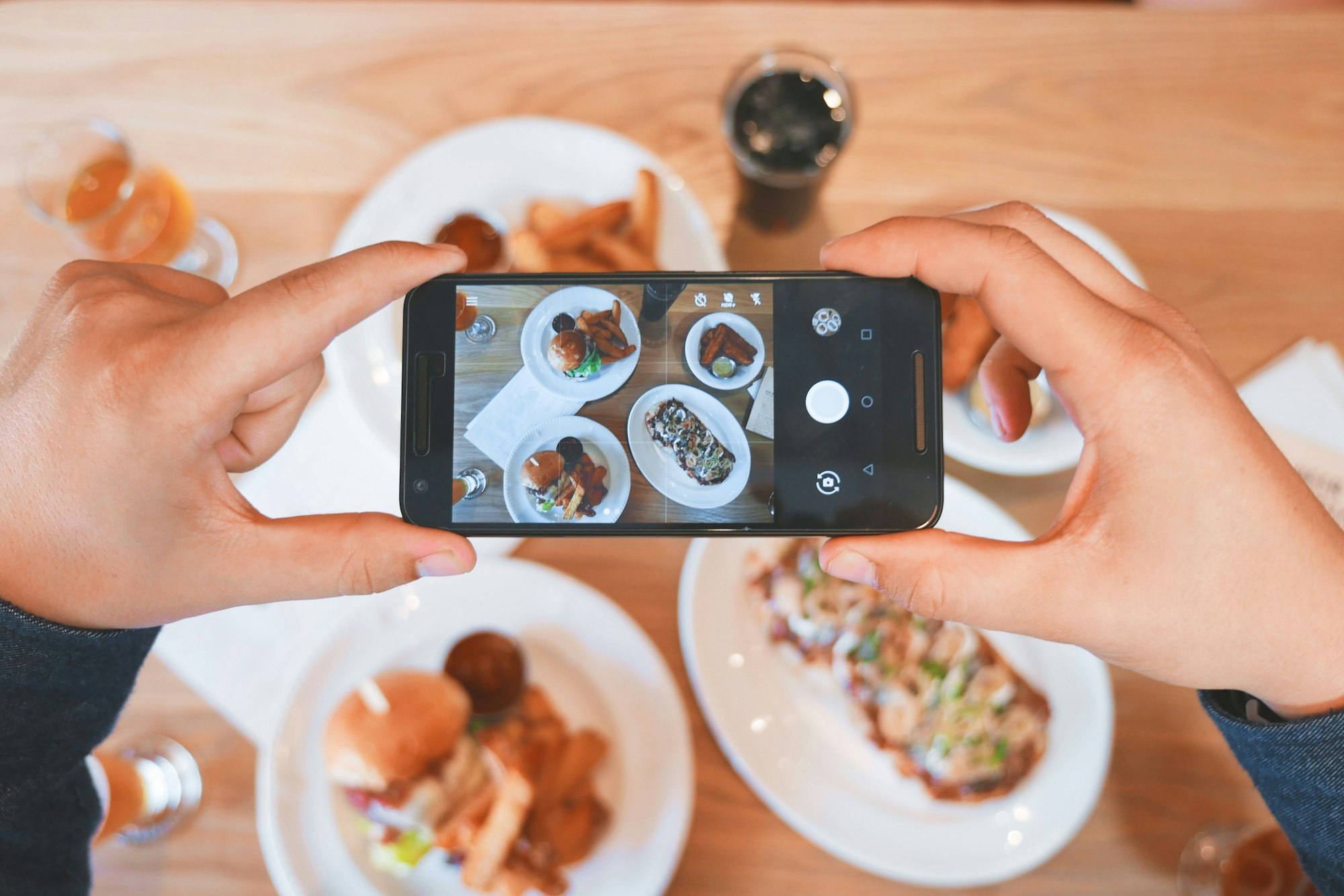 Person taking a social media picture of happy hour food with their phone