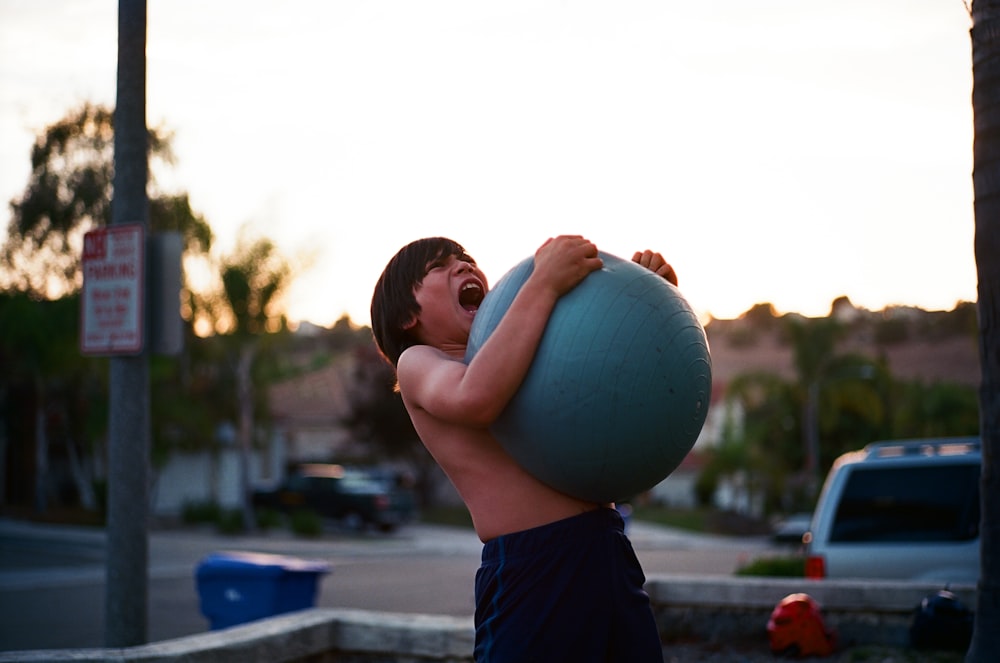 boy's hugging yoga ball while opening mouth