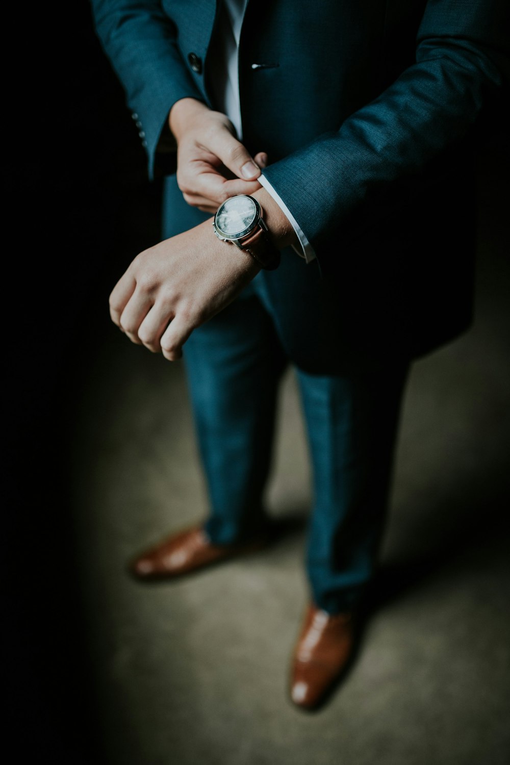 A man in an elegant suit adjusting the sleeve of his shirt