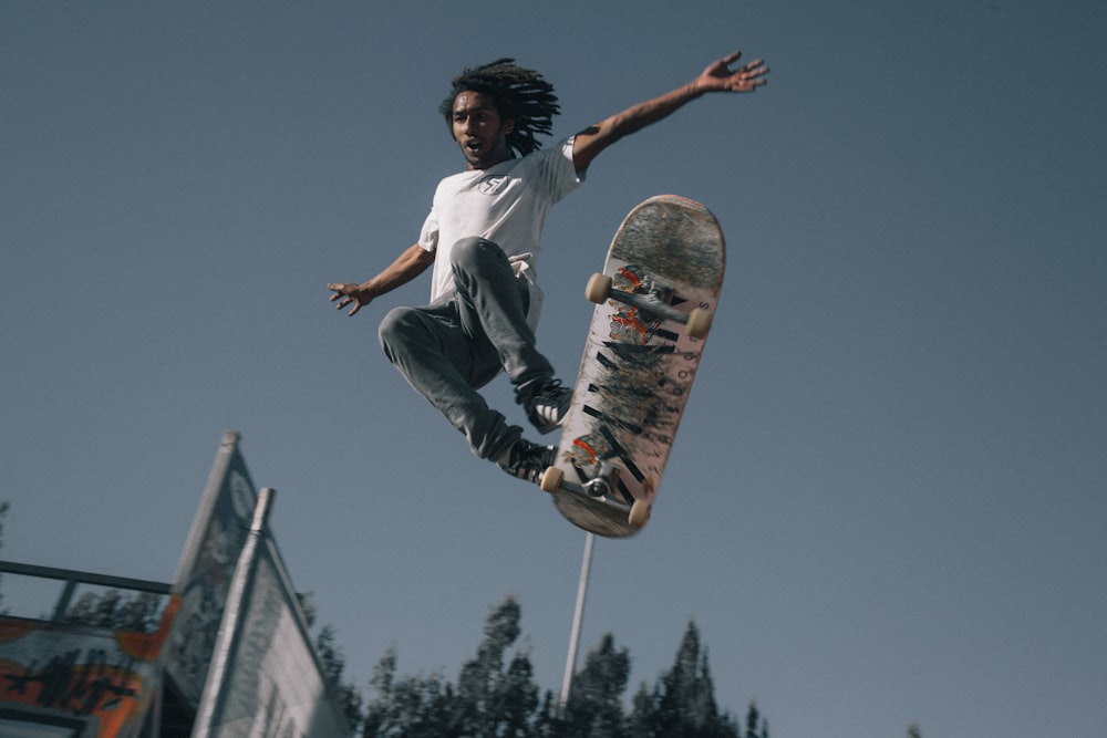 uomo che indossa una maglietta bianca usando lo skateboard