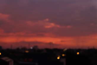 Soft-focus photo of a city skyline at dusk with glowing lights and a calming purple sky.