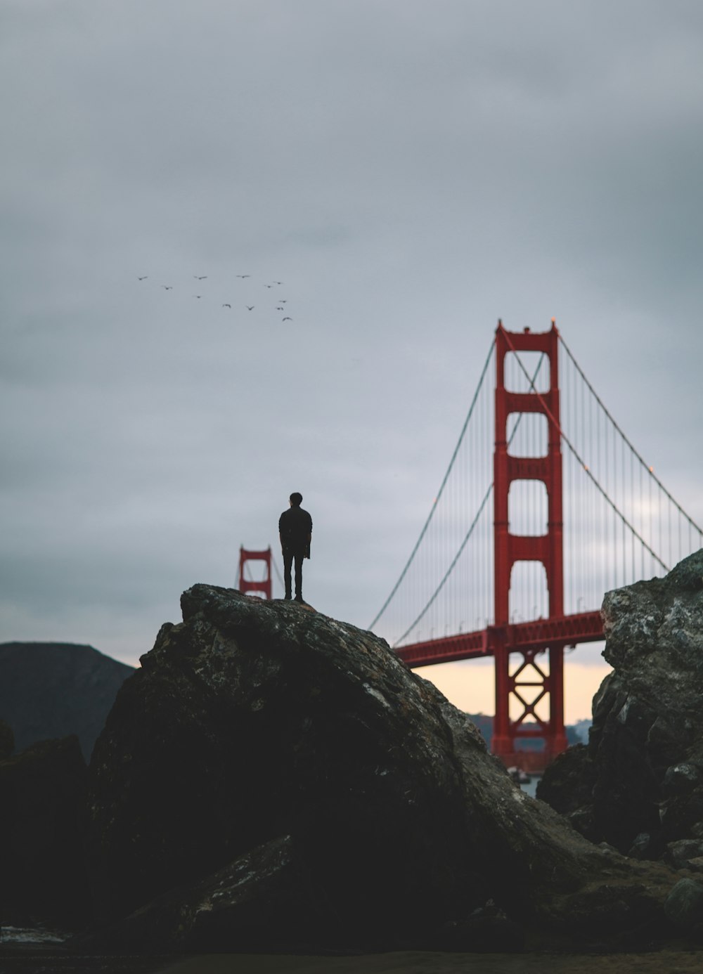 Silhouette eines Mannes, der auf einem Felsen in der Nähe der Golden Gate Bridge steht