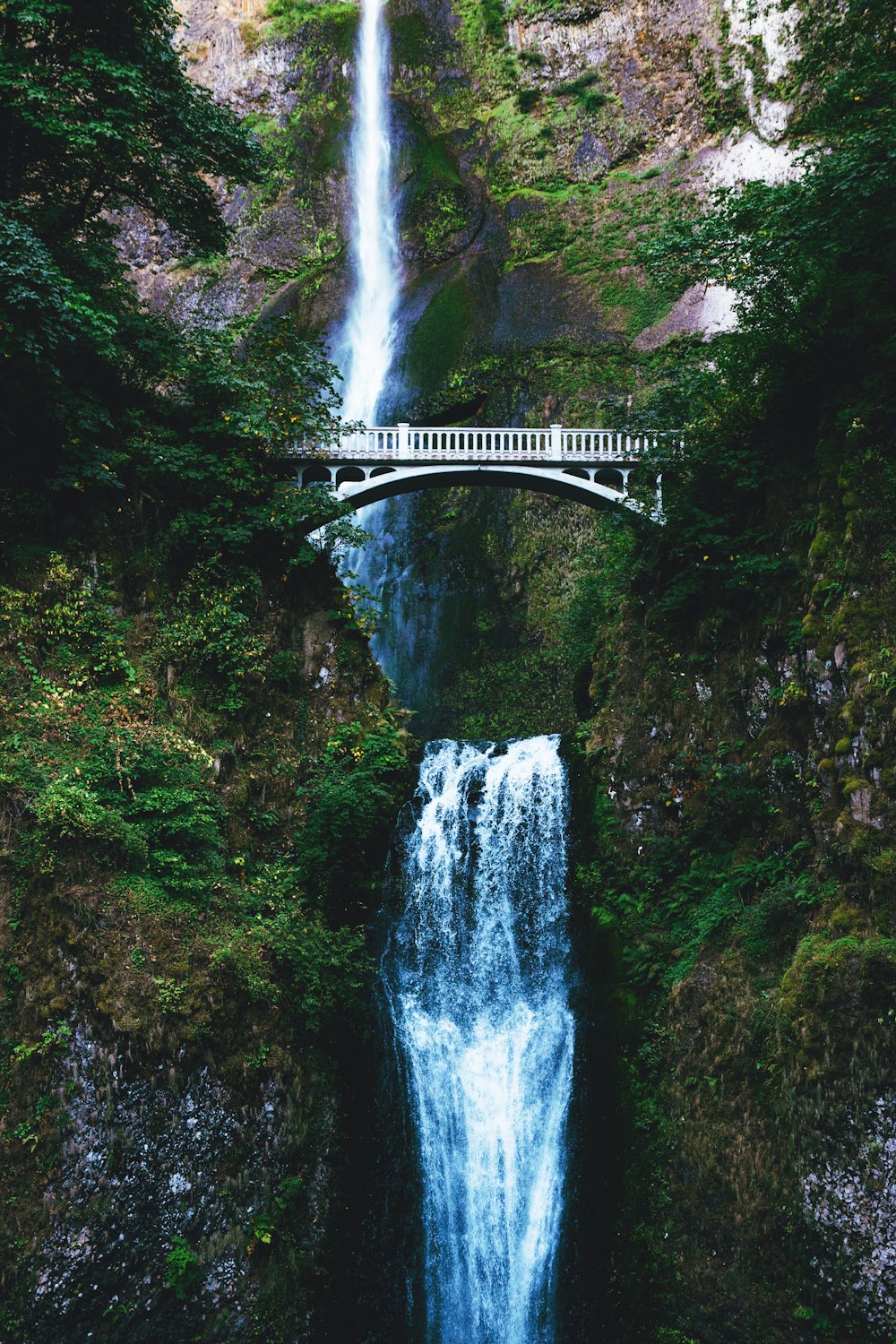 white bridge over waterfalls during daytime