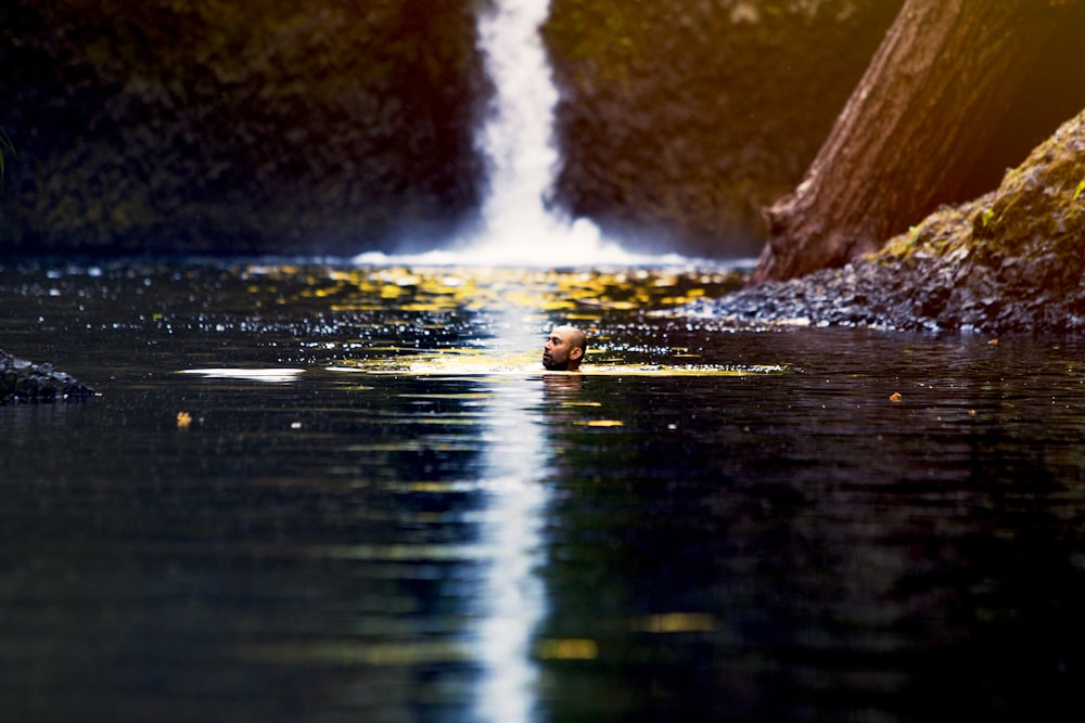 man swimming on waterfall puddle