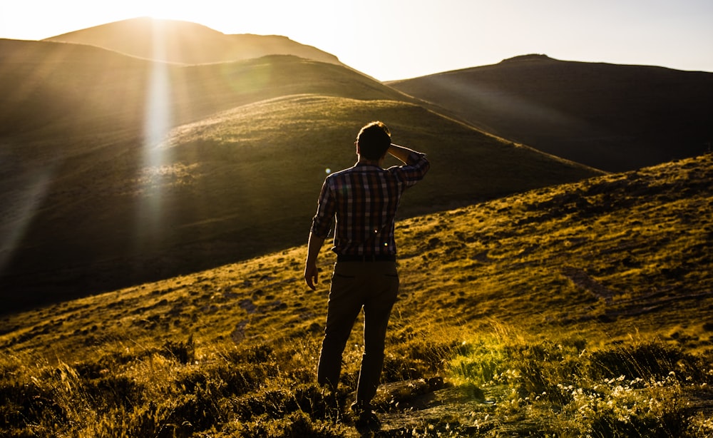 man standing on hill under white sky at daytime