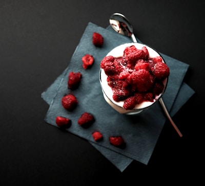 bowl of red strawberries beside silver spoon