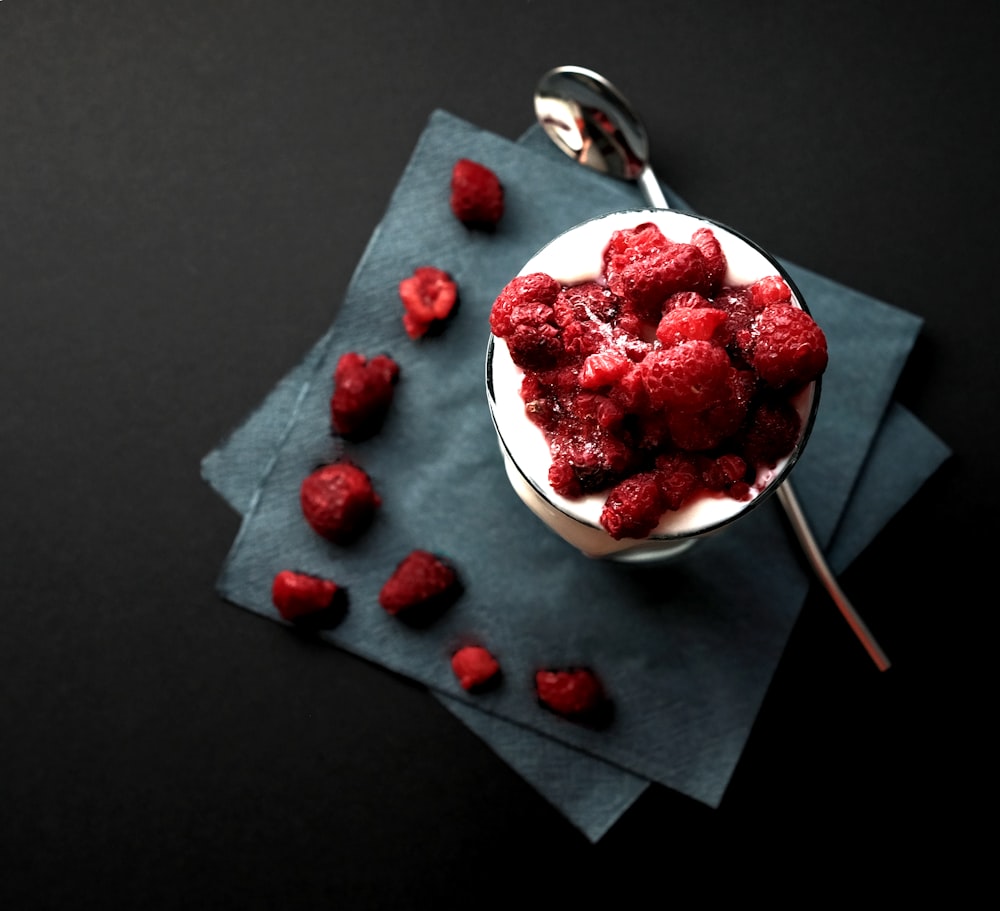 bowl of red strawberries beside silver spoon