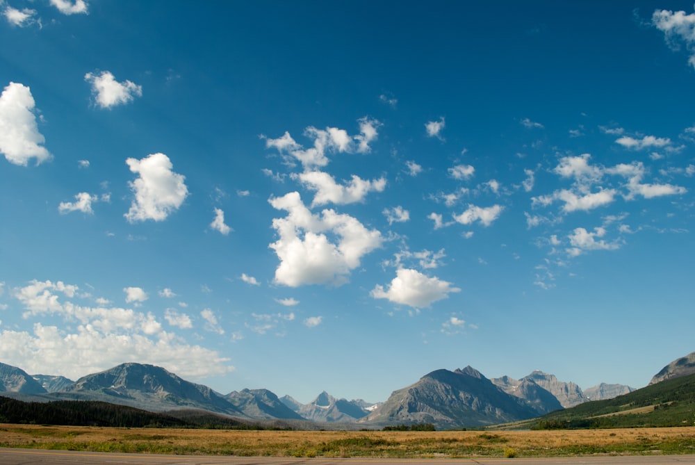 Campo marrón bajo cielo azul y nubes blancas durante el día