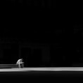 grayscale photogaphy of man sitting on concrete bench