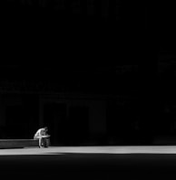 grayscale photogaphy of man sitting on concrete bench