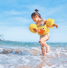 girl playing beside body of water during daytime