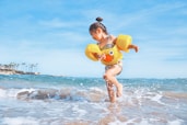 girl playing beside body of water during daytime