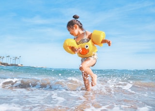 girl playing beside body of water during daytime