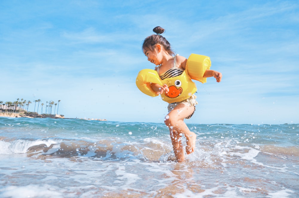 Klein meisje met zwembandjes spelend in de zee