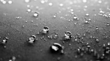 Close-up of water droplets scattered across a textured fabric surface, creating a reflective, glistening effect.